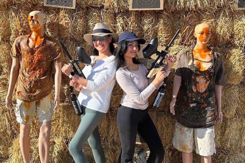 Three people holding rifles and two mannequins with paint splatters. 5