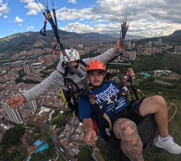 Two people paragliding over a cityscape with mountains in the background. 3