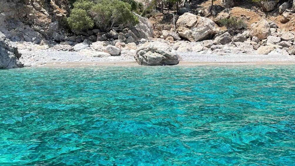 Clear turquoise water, a rocky shoreline, and sparse vegetation. 2