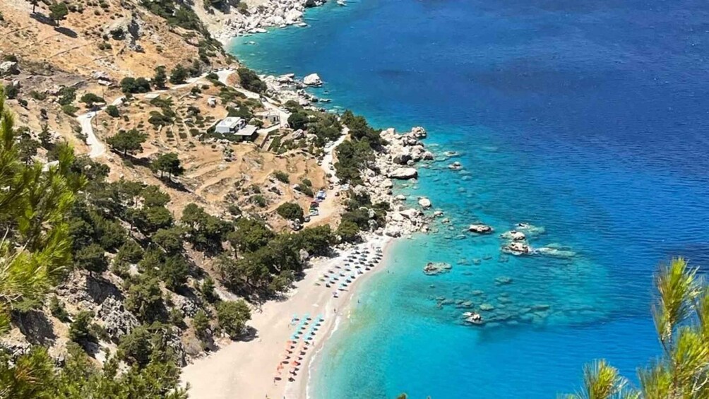 A coastal landscape with a beach, rocky shoreline, and clear blue waters. 4