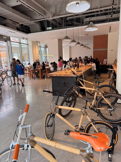 A spacious indoor area with multiple tables and chairs, bicycles parked in the foreground, and people dining and walking around. 3