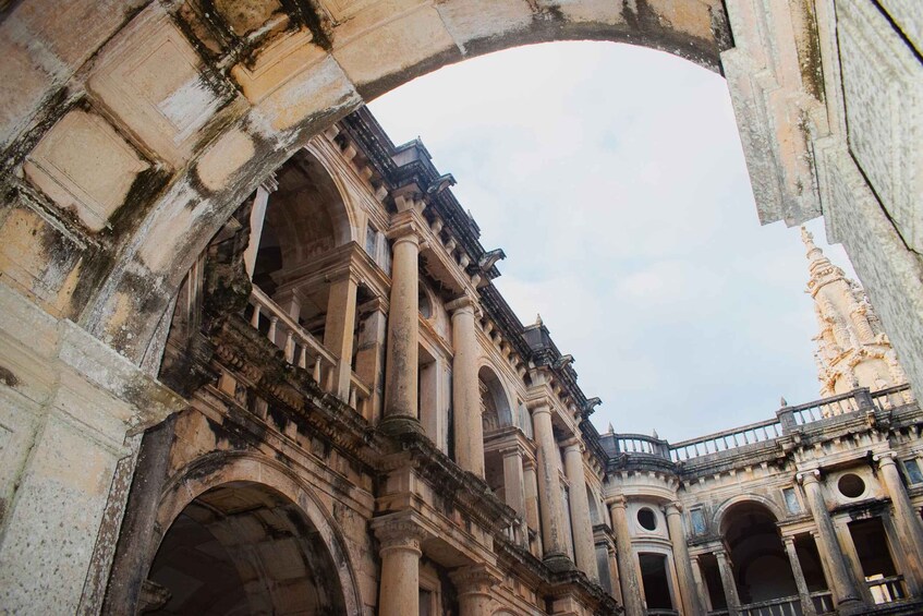 An ancient, ornate building with large arches and columns, featuring intricate stonework and a prominent statue. 5