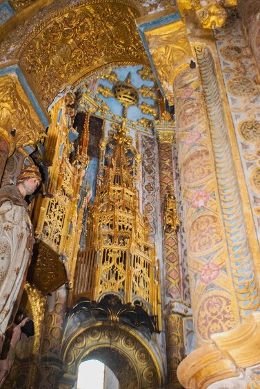 An ornate interior with golden architectural details and a large archway. 4