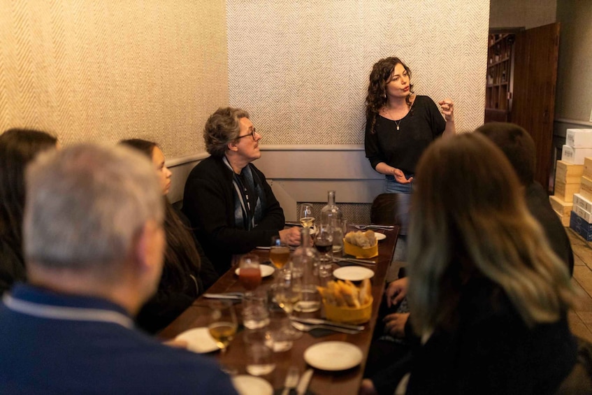 A group of people seated at a dinner table with food and drinks. 3