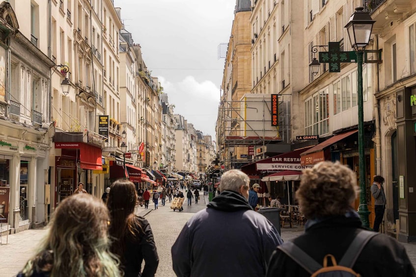 A bustling urban street lined with historic buildings, shops, and outdoor seating areas. 5