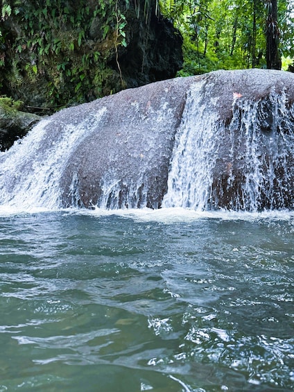 A waterfall cascading over a rock formation surrounded by lush greenery. 3