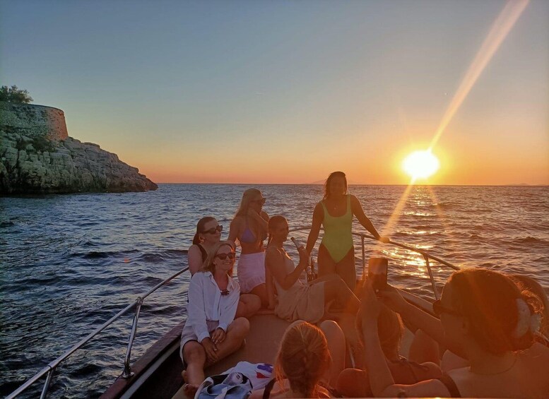 A group of people on a boat at sunset with the sun low on the horizon. 5
