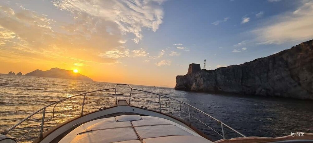 A boat's bow with a sunset and cliffs in the background. 1