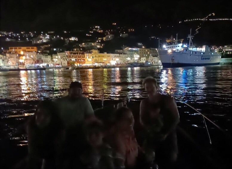 A group of people on a boat with a cityscape and a large ship in the background. 3