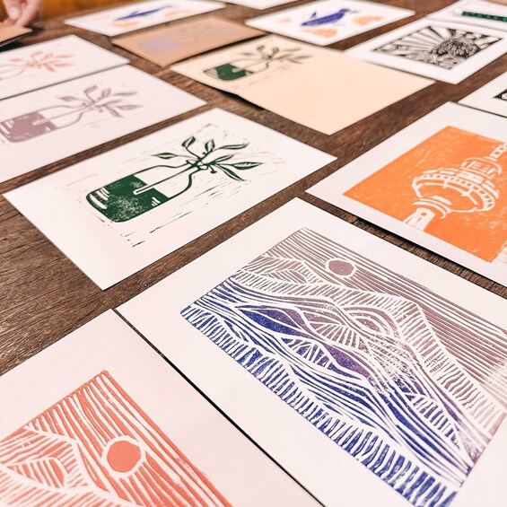 A collection of printed artwork on paper, featuring various designs including a green bottle, a blue and white abstract pattern, and an orange and white structure resembling a tower. 5