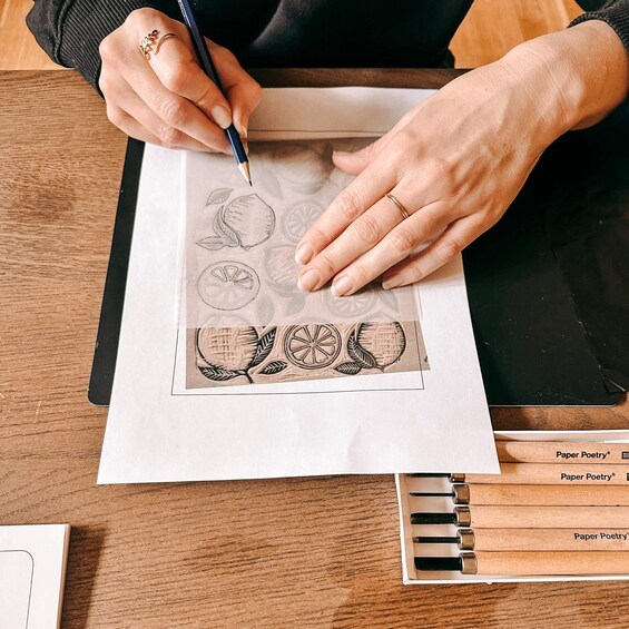 A person drawing fruit designs on paper with a pencil. 4