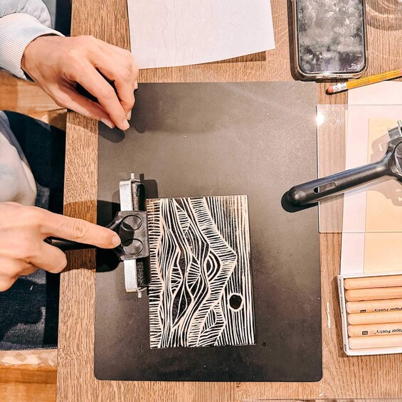 A person using a wood cutting tool on a patterned paper. 2