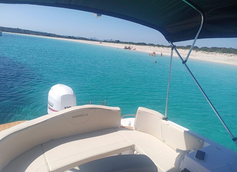 A boat with a white motor and 'MARINELLO' branding, heading towards a beach with clear turquoise water and people swimming. 2