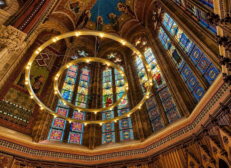 A cathedral interior with ornate stained glass windows and a circular arrangement of lights. 4