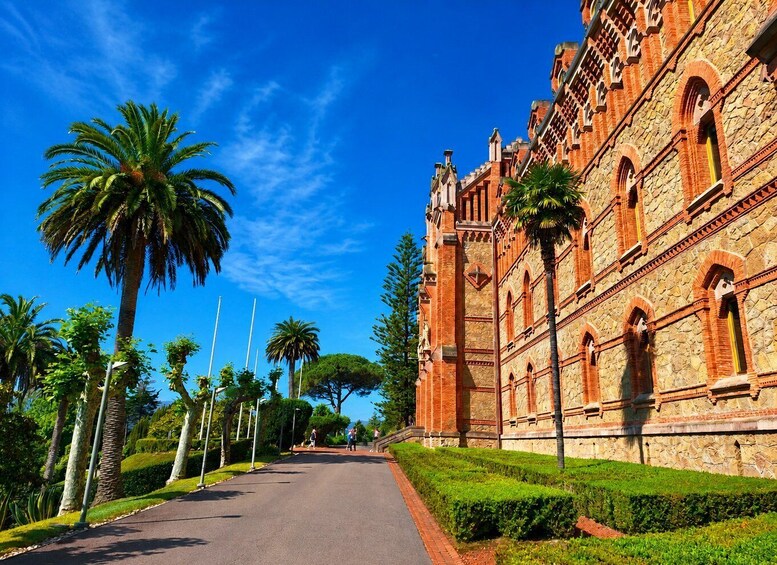 A historic building with red brick architecture, palm trees, and a clear blue sky. 3