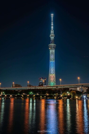 A brightly lit tower with a complex lattice structure, reflecting on the water surface. 4