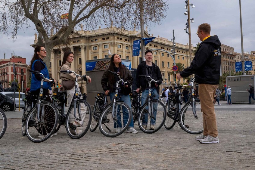 A group of people on bicycles in an urban setting with historic architecture in the background. 3