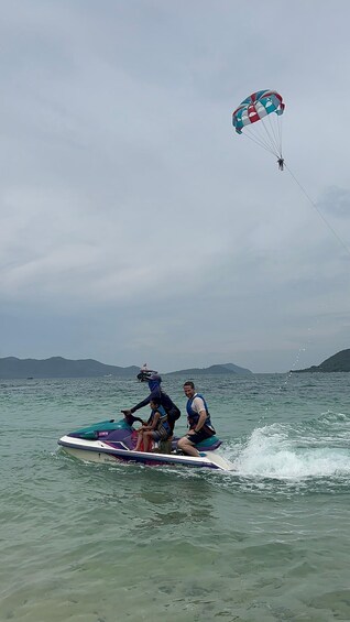 A person riding a jet ski on water with a parachute in the background. 3