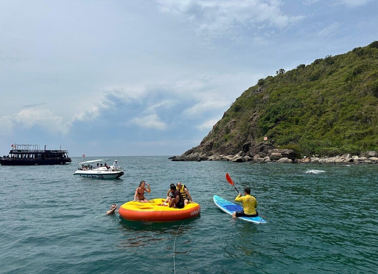 People on a boat, a person on a paddleboard, and a rocky coastline. 2