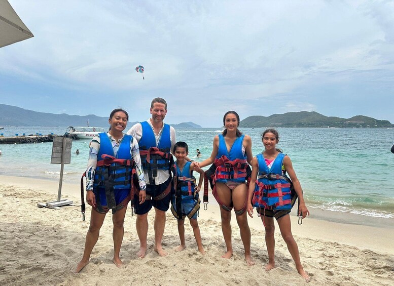 A group of people on a beach with life jackets, a lifeguard tower, and a boat in the background. 1