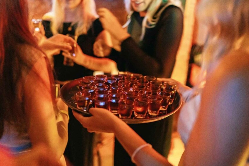 A person holding a tray with shot glasses. 5