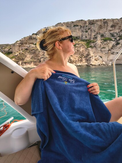 A person on a boat holding a blue towel with text on it. 5