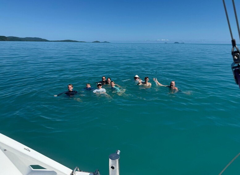 A group of people swimming in a clear blue sea with distant islands. 3