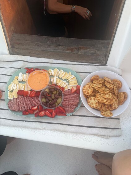 A tray of assorted snacks including cheese, crackers, and olives. 2