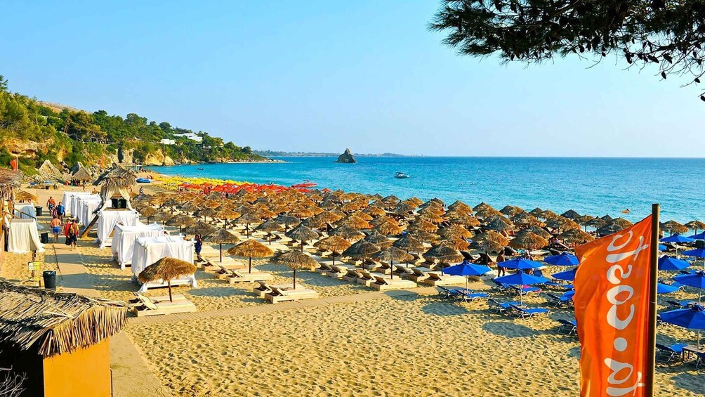 A beach with umbrellas, sun loungers, and a flag. 5