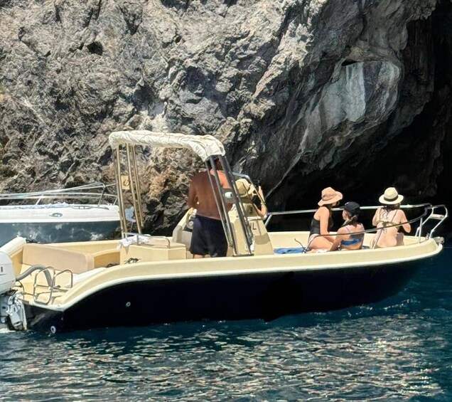 A boat with people on it near rocky cliffs. 2