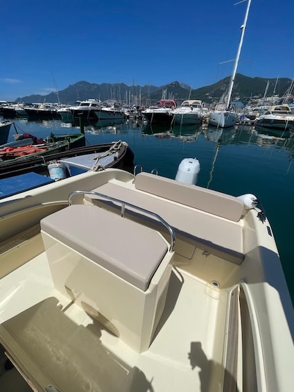 A boat docked at a marina with multiple other boats, a clear blue sky, and mountains in the background. 5