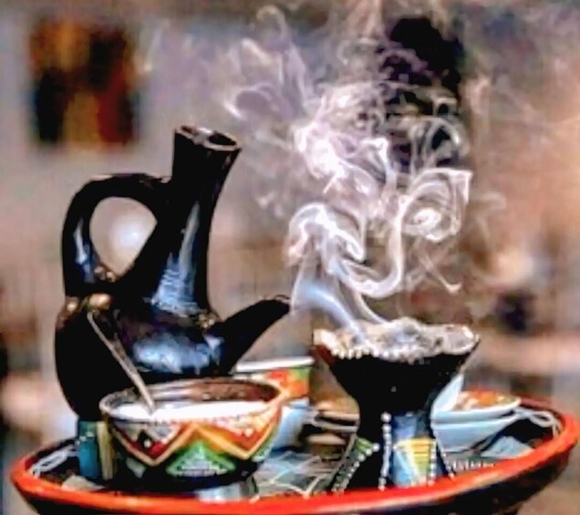 A traditional smoking device with a bowl and a hookah on a colorful tray. 1