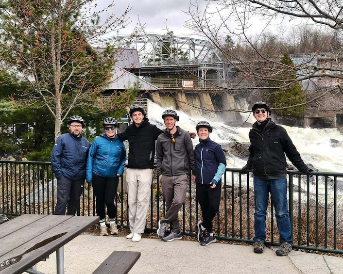A group of people standing by a railing with a waterfall in the background. 4