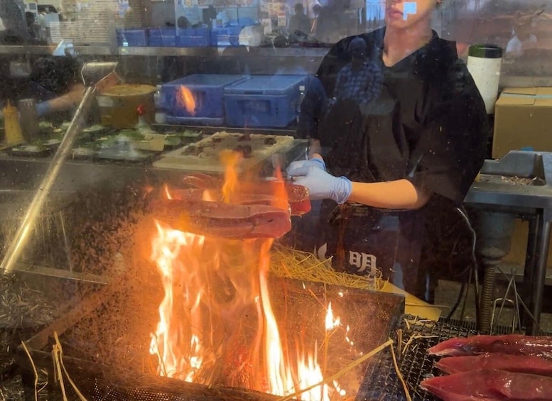 A person grilling meat over an open flame in a kitchen. 4