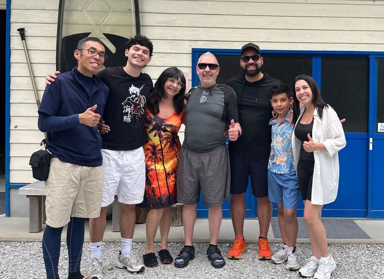 A group of people standing in front of a building with a blue door. 3