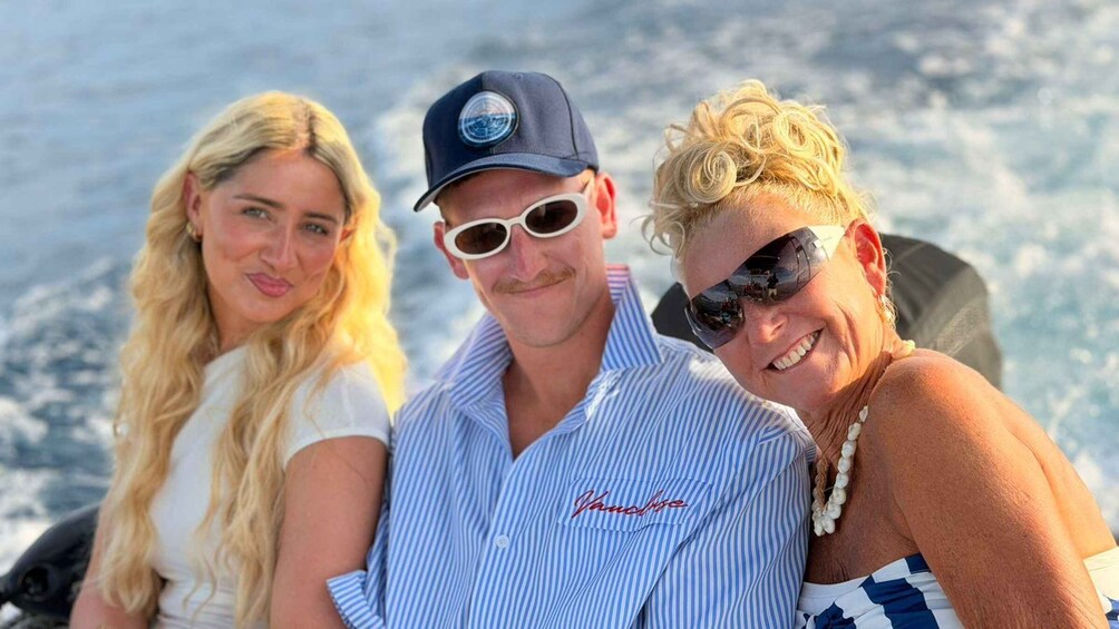 Three people on a boat with a body of water in the background. 2