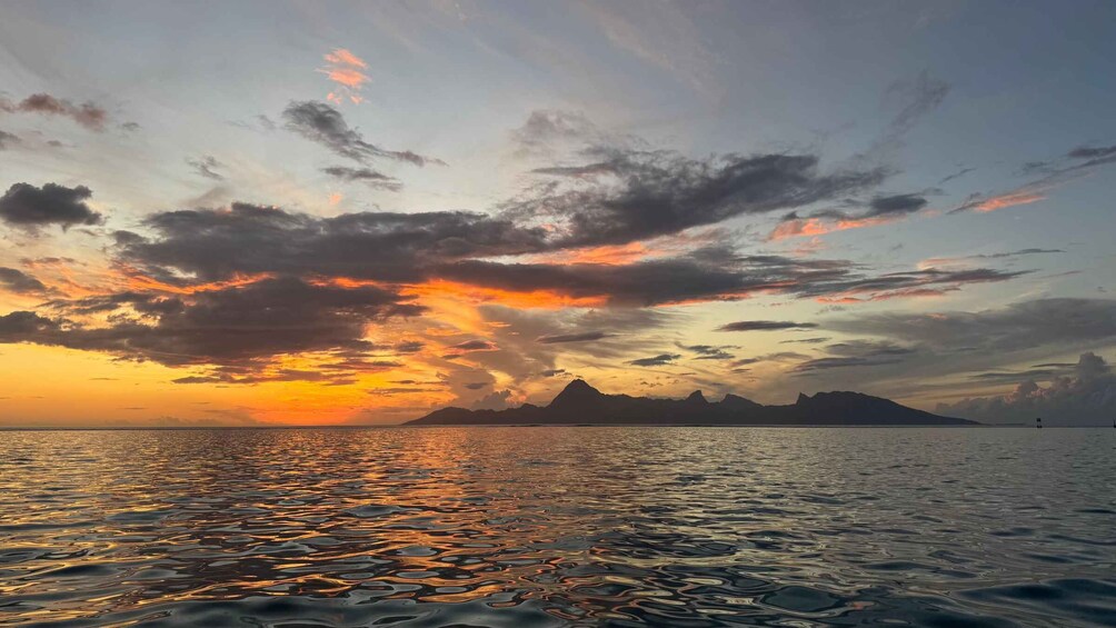 A sunset over a calm sea with a mountain range in the distance. 5
