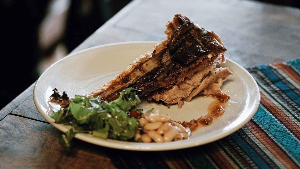 A plate of sliced meat with a side of greens and beans. 3