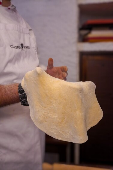 A person holding a large piece of dough. 5