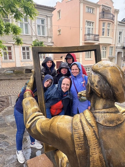 A group of people taking a selfie with a bronze statue of a person holding a mirror. 1