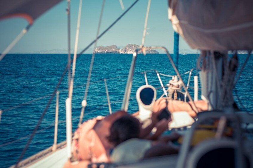 Una persona sdraiata su una barca con vista sul mare e un’isola in lontananza. 3