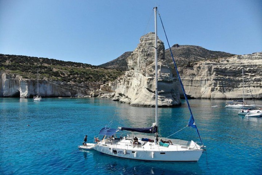 Un velero anclado cerca de una costa rocosa con agua azul cristalina. 2