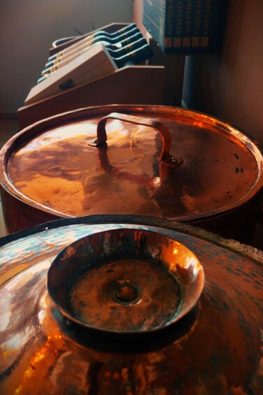 A stack of copper pots with lids, some with handles, and a small bowl in the foreground. 4