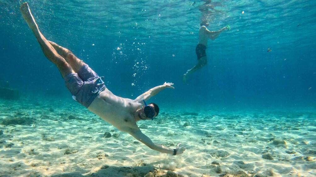 Two people swimming underwater in clear blue water. 2