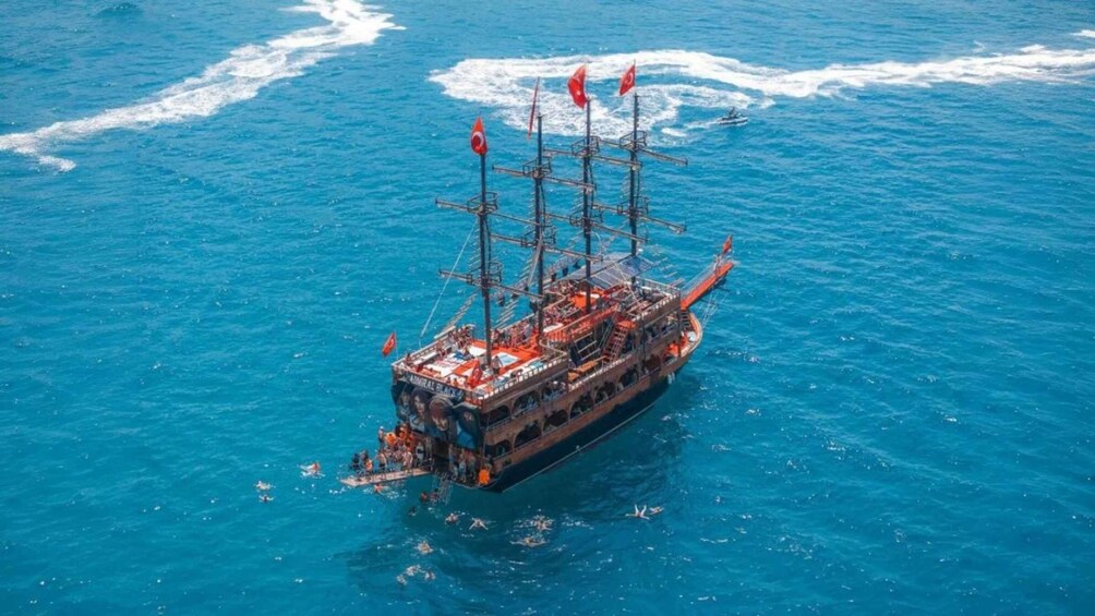 Un grand navire, doté de plusieurs mâts et arborant de nombreux pavillons, voguant sur une mer bleue. 5
