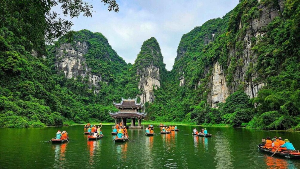 A group of people in boats on a river surrounded by lush greenery and cliffs. 2