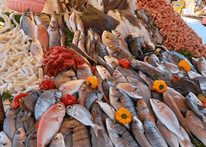 A variety of fresh seafood including fish, squid, and shrimp, displayed in a market setting. 5