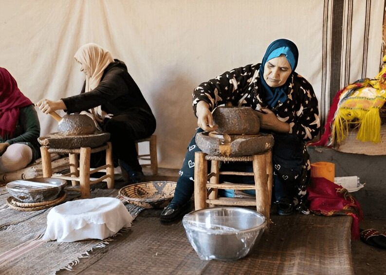 Women engaged in pottery making, seated on stools with pottery wheels, surrounded by bowls and tools. 2