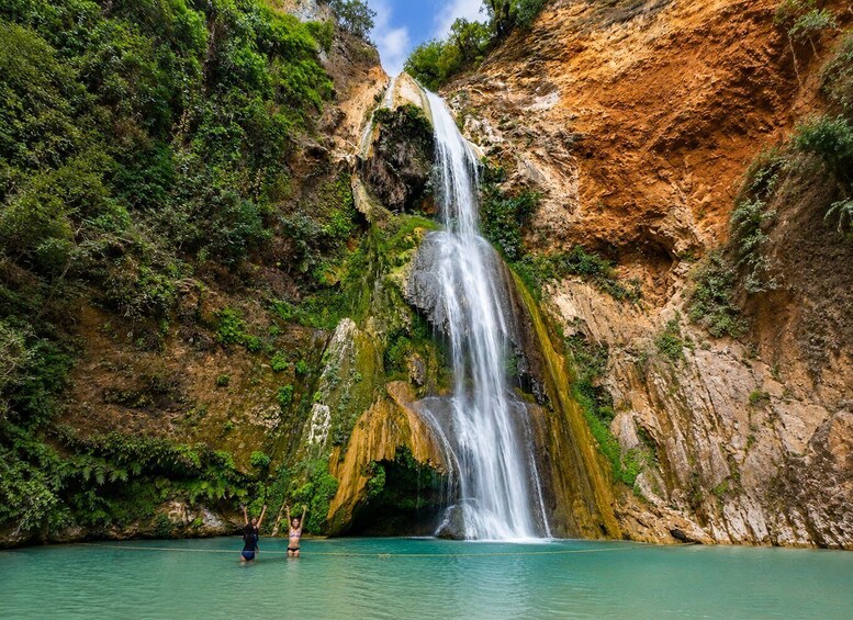 A waterfall cascading into a turquoise pool surrounded by lush greenery and rocky cliffs. 2