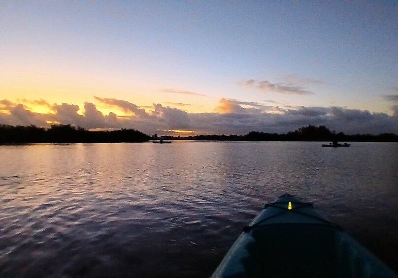 A kayak on calm water during sunset with a clear sky and distant land. 4